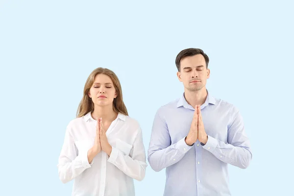 Religious couple praying to God on light color background