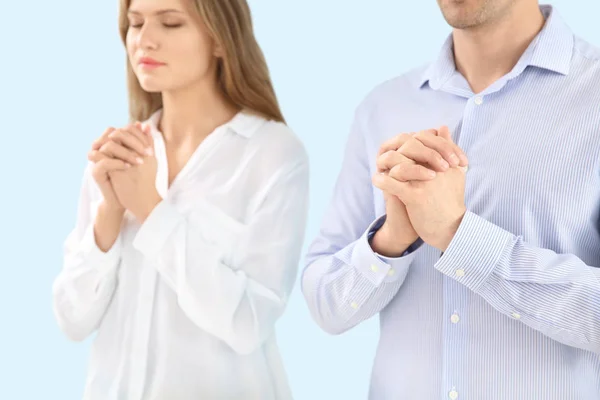 Religious couple praying to God on light color background