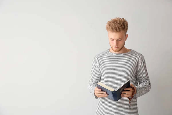 Joven religioso leyendo la Biblia sobre fondo claro — Foto de Stock