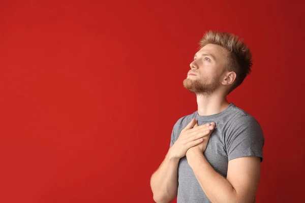 Религиозный юноша молится Богу на цветном фоне — стоковое фото