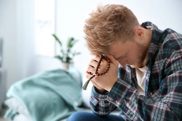 Religious young man praying to God at home — Stock Photo, Image