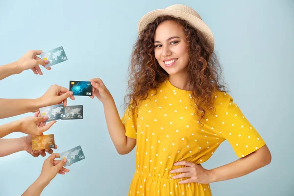 Young African-American woman and hands with credit cards on color background — Stock Photo, Image