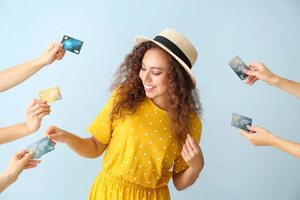 Young African-American woman and hands with credit cards on color background — Stock Photo, Image