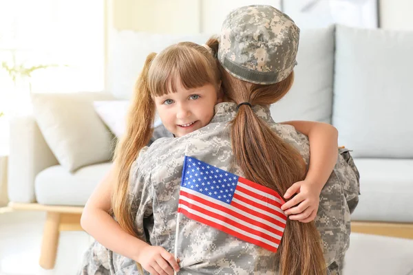 Feliz soldado femenino del ejército de EE.UU. abrazando a su hija pequeña en casa — Foto de Stock