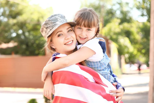 Happy female soldier with her daughter and USA flag outdoors — Stock Photo, Image