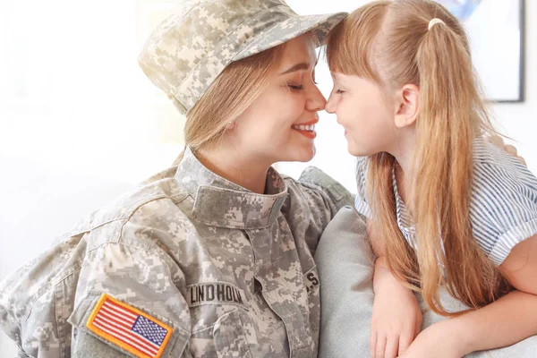 Happy female soldier with her daughter at home