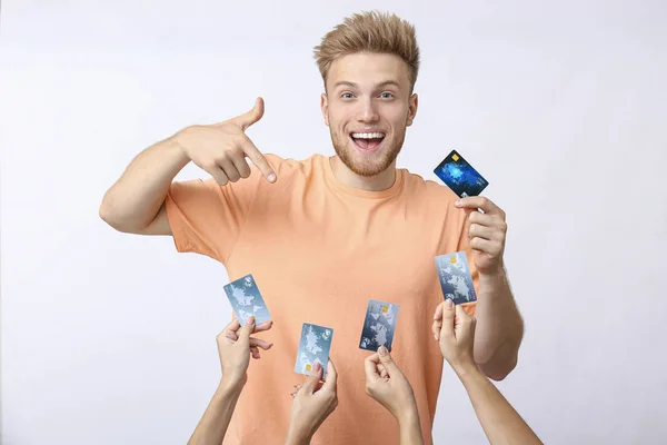 Jovem feliz e mãos com cartões de crédito no fundo branco — Fotografia de Stock