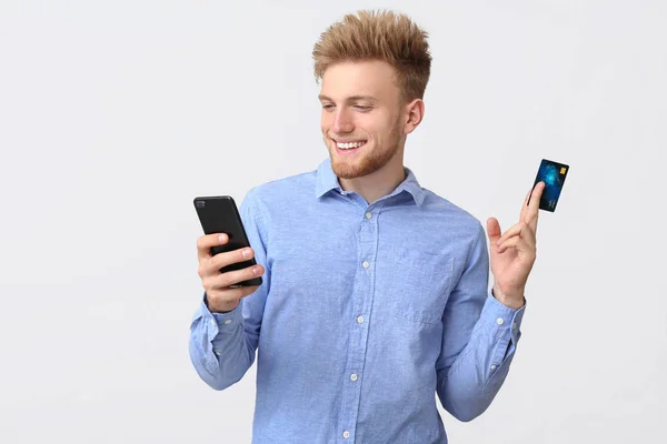 Homme d'affaires heureux avec carte de crédit et téléphone mobile sur fond blanc — Photo