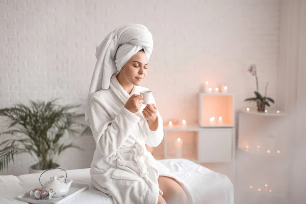 Beautiful young woman with cup of tea relaxing in spa salon — Stock Photo, Image