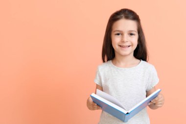 Renklerle ilgili kitabı olan sevimli küçük kız.