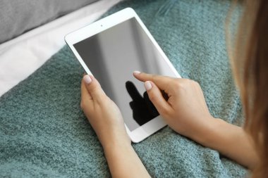 Evde tablet bilgisayarı olan genç bir kadın.