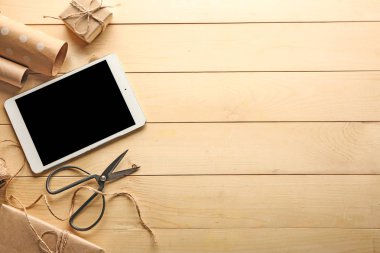 Tablet bilgisayar ve ahşap arka plan üzerinde hediye paketleme için aksesuarlar