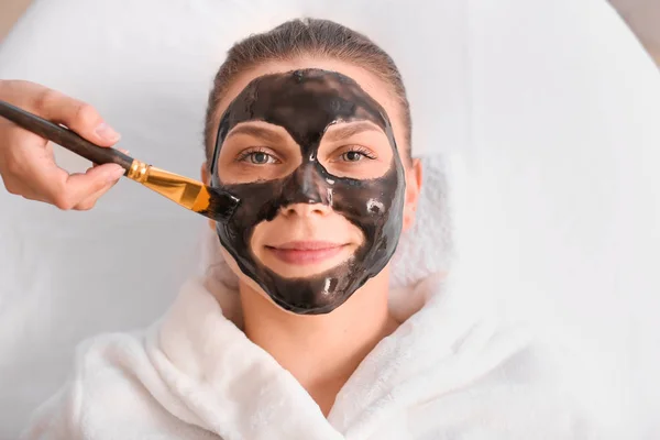 Krásná žena prodělává s obličejovou maskou v salonu krásy — Stock fotografie