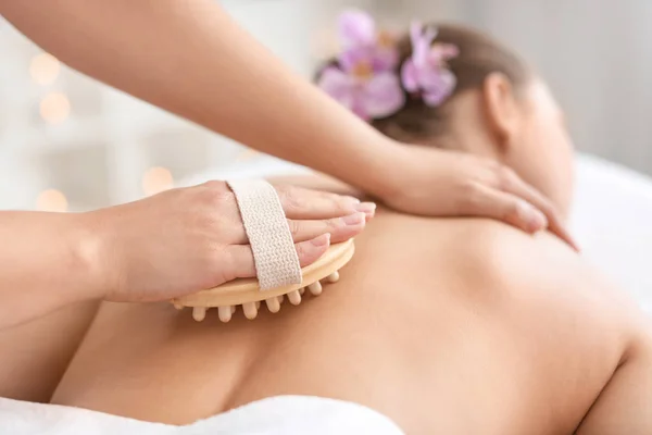 Belle jeune femme recevant un massage avec brosse dans le salon de spa — Photo