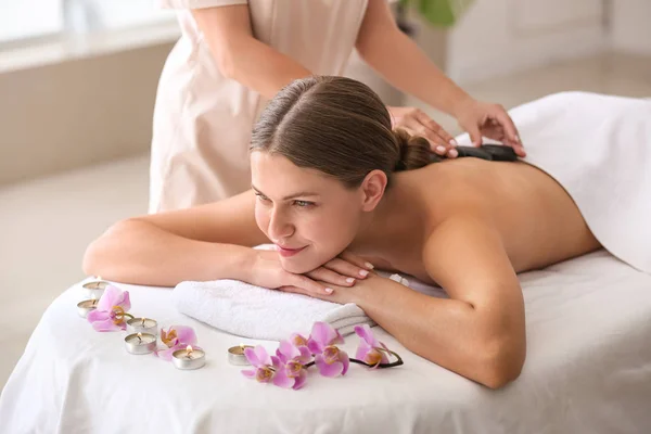 Beautiful young woman undergoing treatment with hot stones in spa salon — Stock Photo, Image