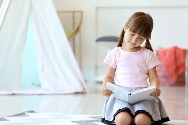 Cute little girl reading book at home — Stock Photo, Image