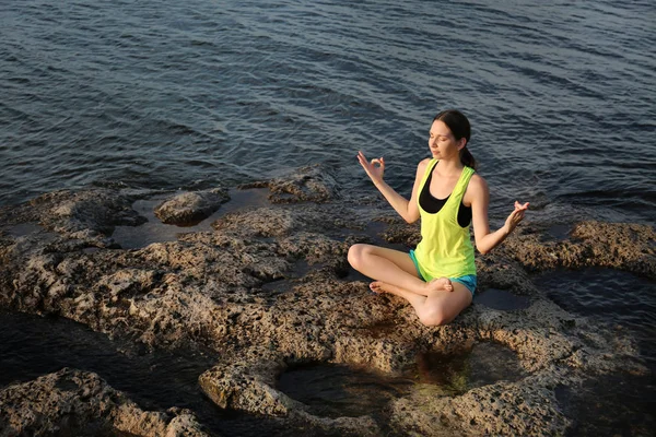 Young woman meditating near river — Stock Photo, Image