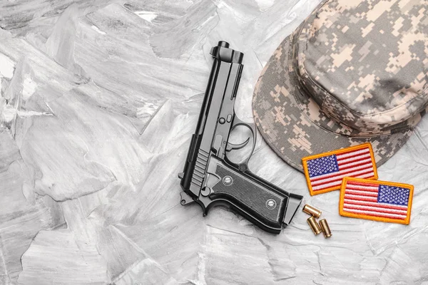 Військова шапка, пістолет і шеврони на сірому фоні — стокове фото