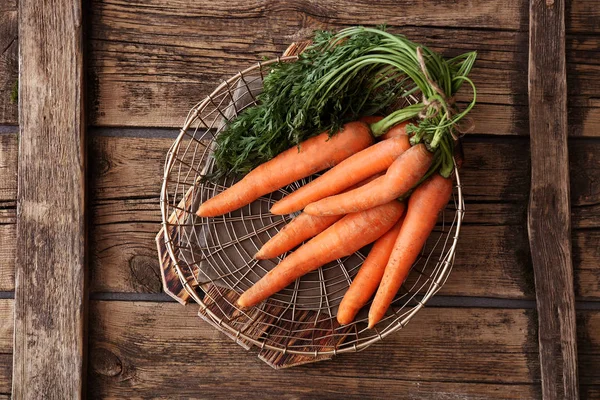 Basket with fresh carrots on wooden table — Stock Photo, Image