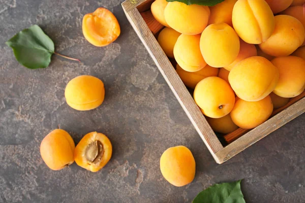 Boîte de savoureux abricots mûrs sur table grise — Photo
