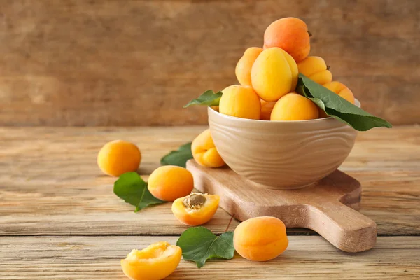 Miska s chutnými zralými meruňky na dřevěném stole — Stock fotografie