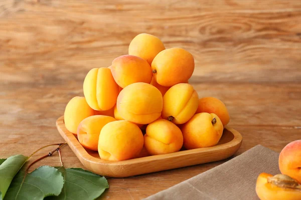 Plate with tasty ripe apricots on wooden table — Stock Photo, Image