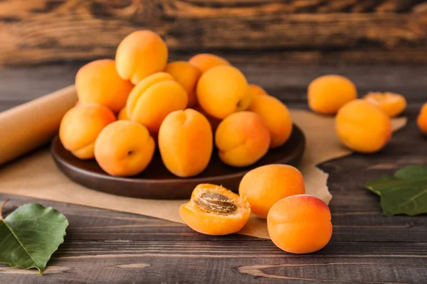 Тарілка зі смачними стиглими абрикосами на дерев'яному столі — стокове фото