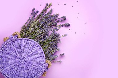 Renk arka plan üzerinde hasır çanta ile güzel lavanta çiçekleri