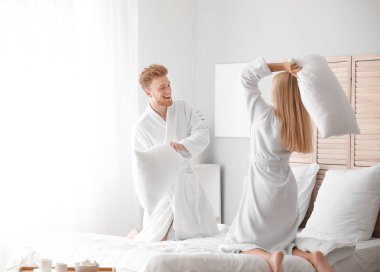 Yatak odasında yastık mücadele mutlu genç çift Sabah