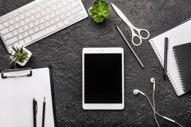 Modern tablet bilgisayar, klavye, kırtasiye, pano ve kulaklıklar koyu arka plan