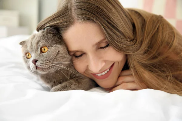 Beautiful woman with cute cat lying in bed at home — Stock Photo, Image