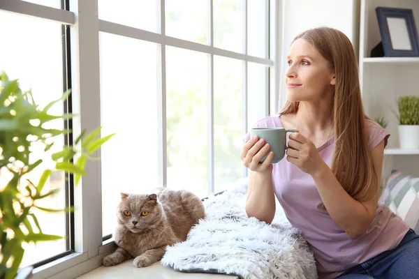Beautiful woman with cute cat near window at home — Stock Photo, Image