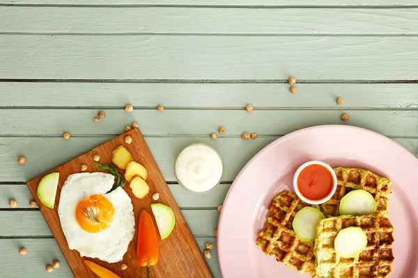 Plate with tasty squash waffles, sauces and fried egg on wooden table — Stock Photo, Image