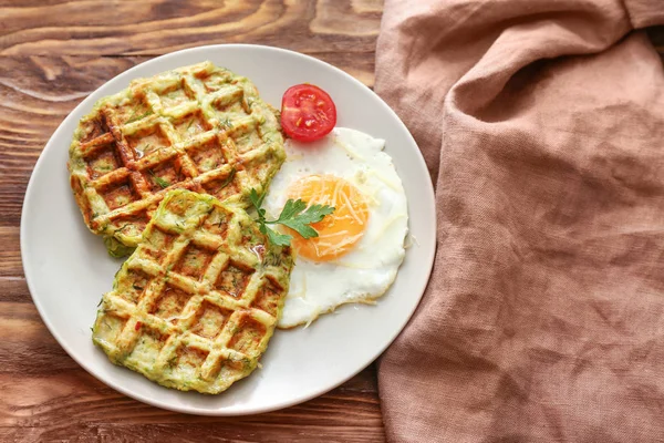 Тарелка с вкусными вафлями из сквоша и яичницей на деревянном столе — стоковое фото