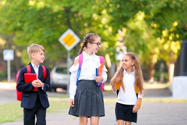Милые маленькие ученики переходят дорогу — стоковое фото