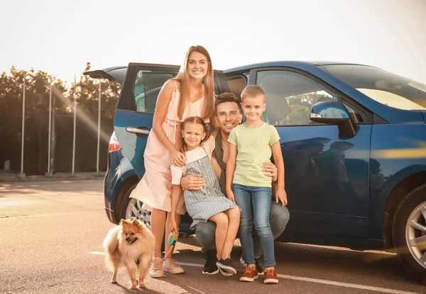 Família feliz com cão perto do carro ao ar livre — Fotografia de Stock