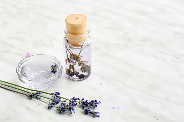 Lavender flowers with essential oil on light background — Stock Photo, Image