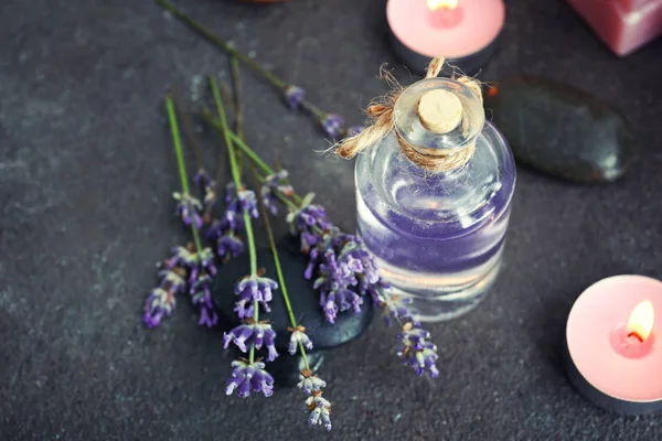 Bottle of lavender essential oil and candles on grey table — Stock Photo, Image