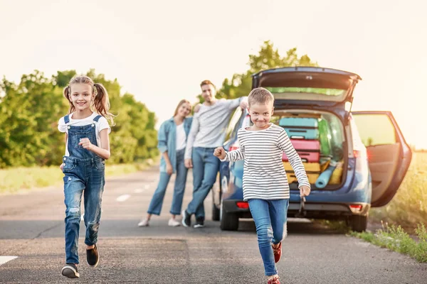 Gelukkige kinderen en hun ouders in de buurt van auto buitenshuis — Stockfoto