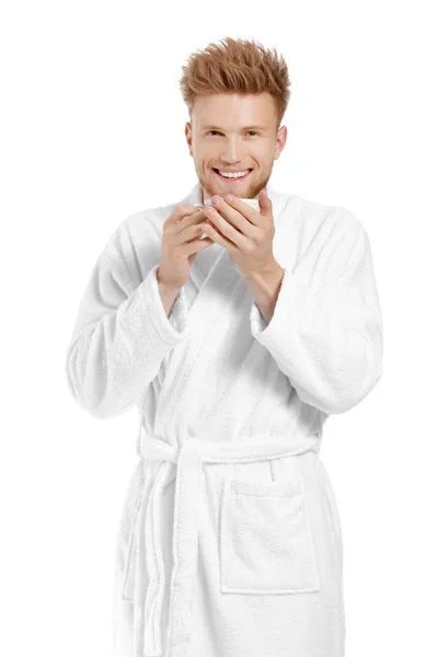 Handsome young man in bathrobe drinking coffee on white background — Stock Photo, Image