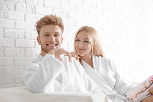 행복한 젊은 부부는 집에서 소파에 앉아 목욕 가운에 — 스톡 사진