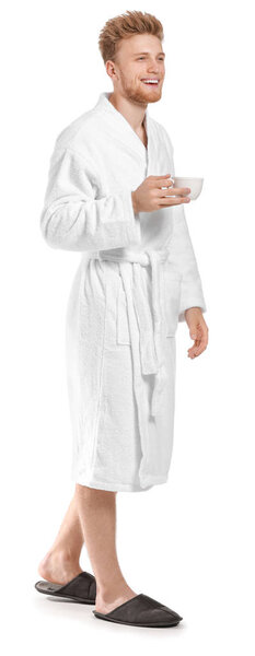 Красивый молодой человек в халате пьет кофе на белом фоне
