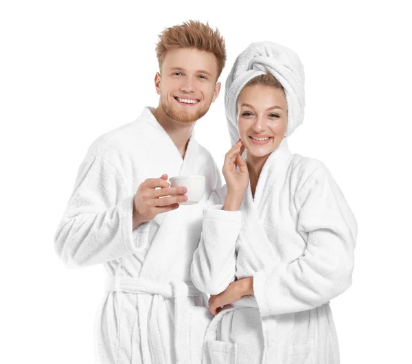 愉快的年轻夫妇穿着浴袍，在白色背景上喝杯咖啡 — 图库照片