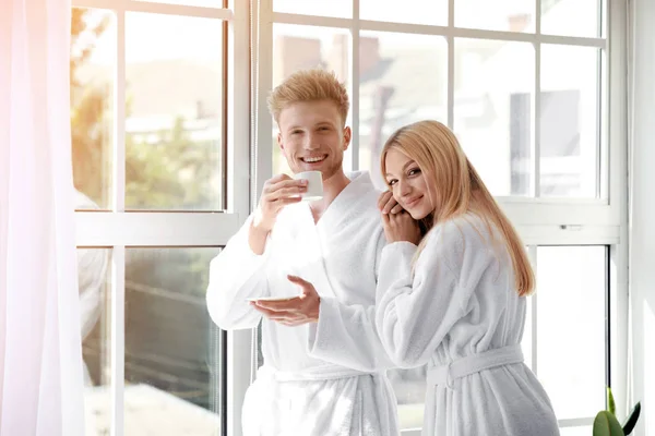 Ráno šťastných mladých pár v županech u okna — Stock fotografie