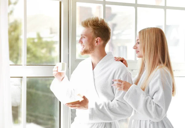 아침 의 행복한 젊은 커플 에 목욕 가운 근처 창 — 스톡 사진