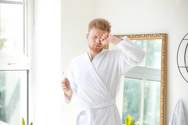 Morning of sleepy young man with toothbrush in bathroom — Stock Photo, Image