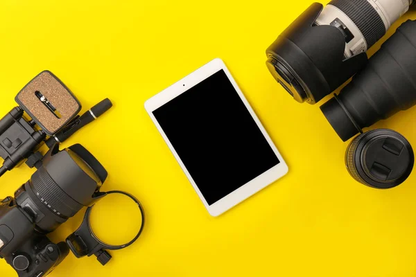 Tablet computer and set of photographer's equipment on color background — Stock Photo, Image