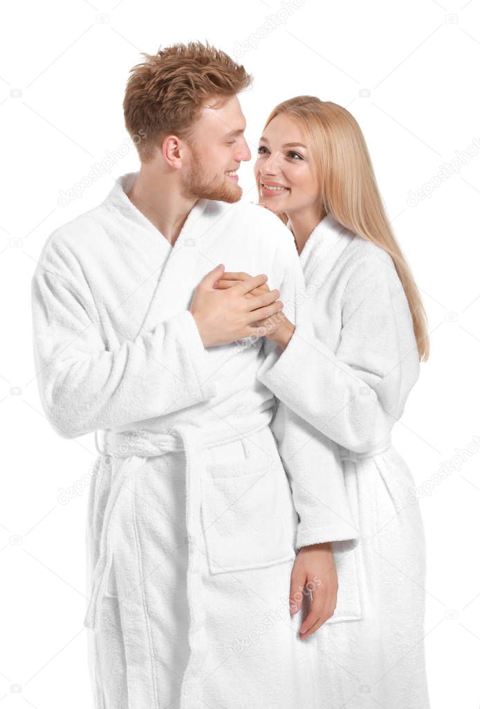 Happy young couple in bathrobes on white background