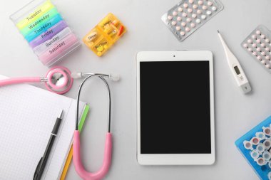 Tablet bilgisayar, pano, stetoskop ve hafif arka plan üzerinde haplar