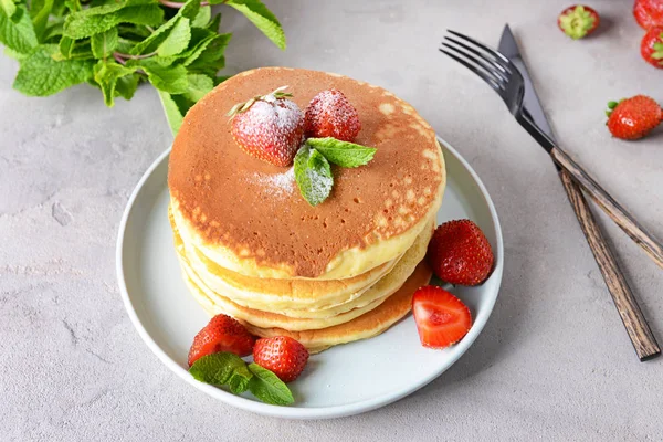 Teller mit leckeren Pfannkuchen und Erdbeeren auf dem Tisch — Stockfoto